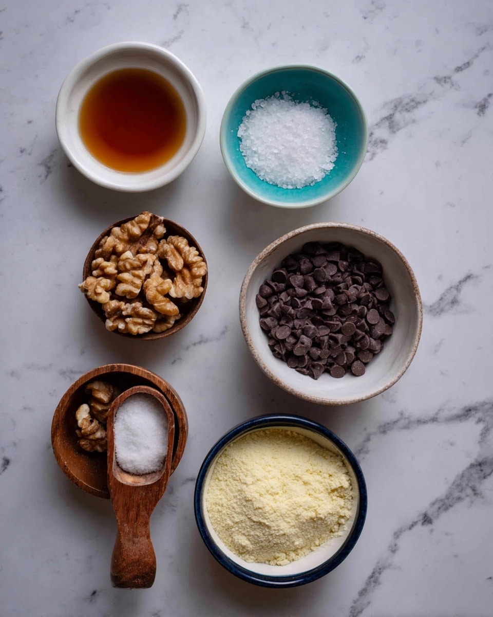 The image shows six containers with ingredients placed on a white marbled surface. At the top left, there is a white bowl with a dark amber liquid. Next to it, at the top center, is a small teal bowl holding coarse salt crystals. To the right of the salt bowl, there is a white bowl filled with dark brown chocolate chips. Below the chocolate chips, a deep blue-rimmed white bowl is filled with a pale yellow powder. On the bottom left, a wooden measuring cup holds walnut pieces, and just above it, another wooden measuring cup contains a scoop of white coconut oil. The arrangement is neat, with the bowls and cups evenly spaced. photo taken with an iphone --ar 4:5 --v 7