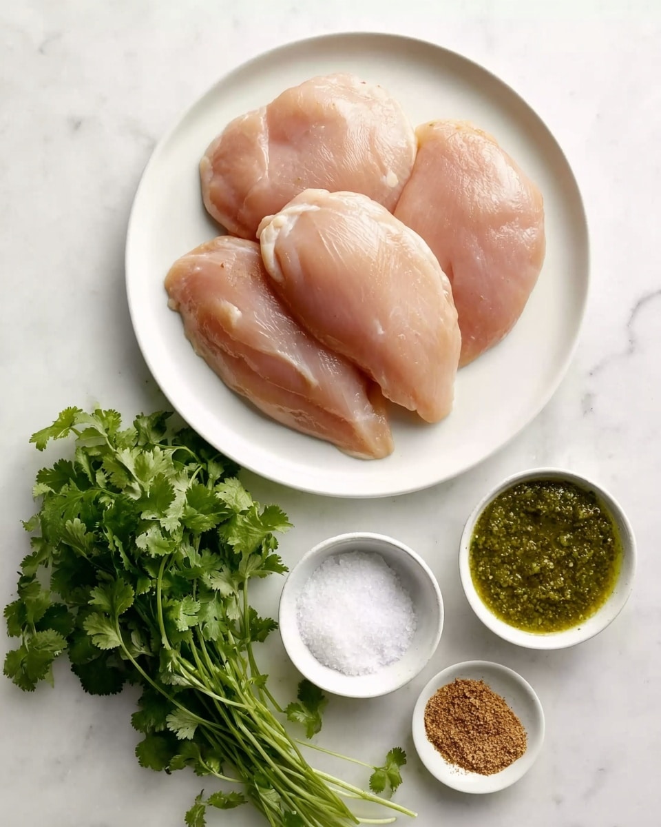 A white plate holds four raw chicken breasts arranged in a loose circle, showing their smooth, pale pink texture. Below the plate, a bunch of fresh green cilantro lies on the white marbled surface. Next to the cilantro, there are three small white dishes: one with coarse white salt, another with a brown spice mix, and the largest one filled with a green sauce that looks slightly chunky. The whole setup is simple and clean with bright natural light, highlighting the fresh ingredients photo taken with an iphone --ar 4:5 --v 7