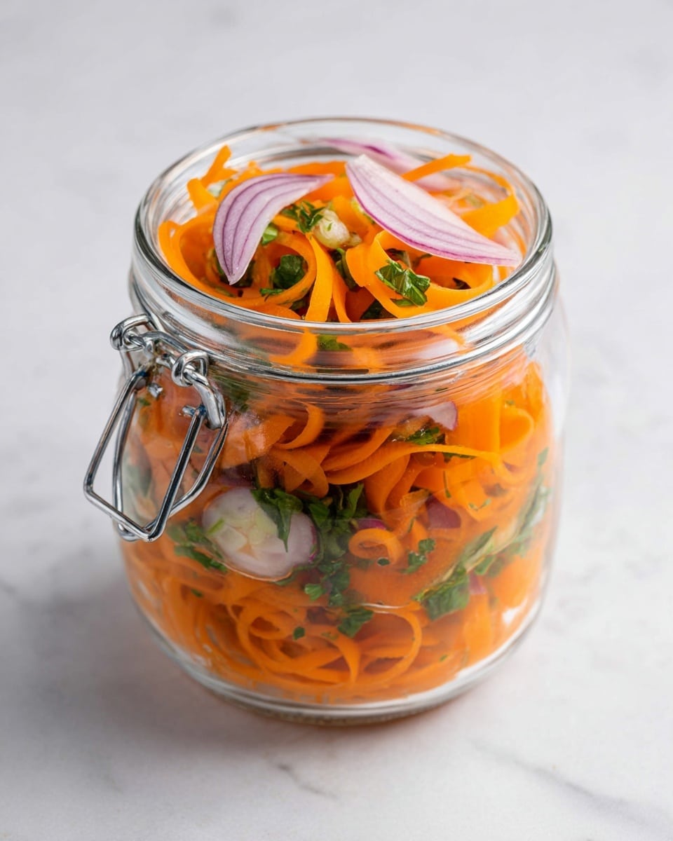 A clear glass jar with a metal clasp is filled with thin, curly orange carrot ribbons layered throughout. There are bright green chopped herbs mixed in between the carrot layers, adding a fresh checkered look. Near the top, there are a few pieces of light purple onion slices resting on the carrots and herbs, giving a slight contrast in color. The jar is placed on a white marbled surface. photo taken with an iphone --ar 4:5 --v 7