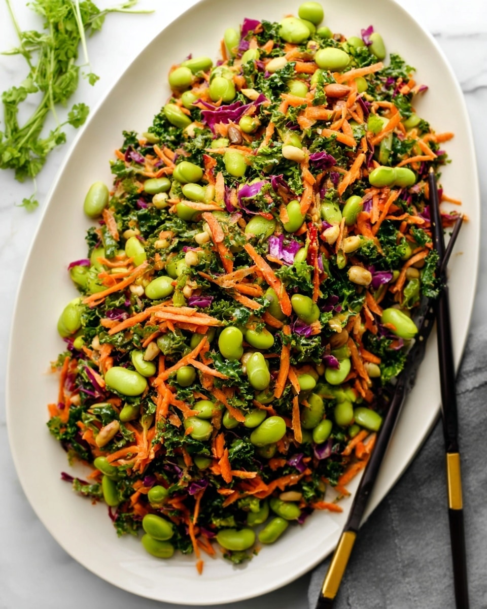 A white oval plate holds a colorful salad with three main layers: a base of bright orange shredded carrots, mixed with dark green curly kale, topped with large light green edamame beans and small pieces of purple cabbage. The salad looks fresh and slightly glossy, suggesting a light dressing. A pair of black chopsticks with gold accents rest on the right side of the plate, partially touching the salad. The plate is set on a white marbled surface, and a sprig of green herbs is visible in the top left corner. Photo taken with an iphone --ar 4:5 --v 7