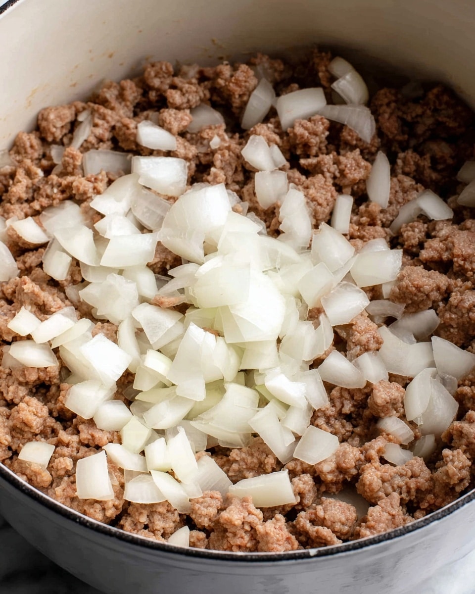 A close-up image of a white pot filled with two layers: the bottom layer has large pieces of browned ground meat in light brown color with a crumbly texture, and scattered on top are chopped white onions in medium-sized chunks with a smooth, shiny surface. The inside material of the pot is a clean white enamel, and the pot sits on a white marbled surface. Photo taken with an iphone --ar 4:5 --v 7