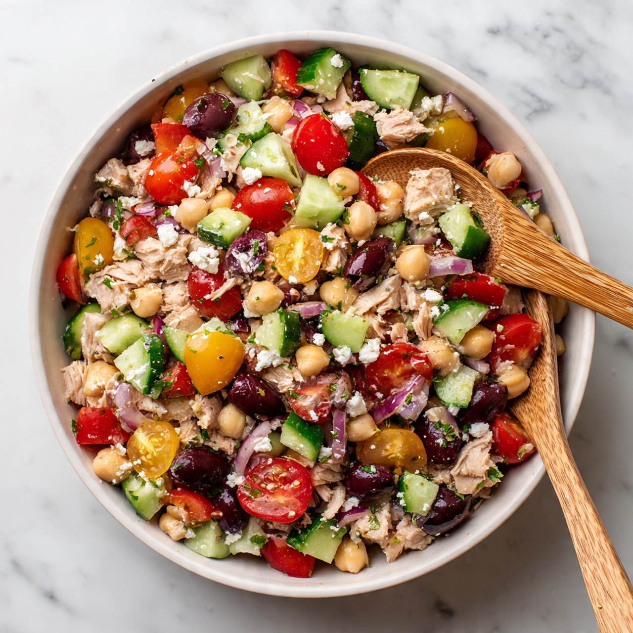The image shows three clear glass jars filled with a colorful layered salad. Each jar contains layers of chopped red and yellow cherry tomatoes, orange bell pepper strips, pieces of cucumber, black beans, chickpeas, and bits of light-colored grains or meat, topped with some small green herbs or lettuce pieces. The jars are placed on a light-colored cloth on top of a white marbled textured surface, with parts of a purple onion and two small tomatoes nearby. The layers inside the jars are vibrant and mixed but still have visible color and texture differences. Photo taken with an iphone --ar 4:5 --v 7