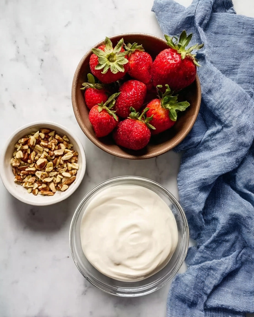 The image shows three items placed on a white marbled surface: a small white bowl filled with chopped nuts at the top left, a medium brown bowl filled with fresh red strawberries with green leaves at the top right, and a clear glass bowl filled with smooth, creamy white yogurt at the bottom left. A blue cloth napkin is laid out on the right side next to the bowls. photo taken with an iphone --ar 4:5 --v 7