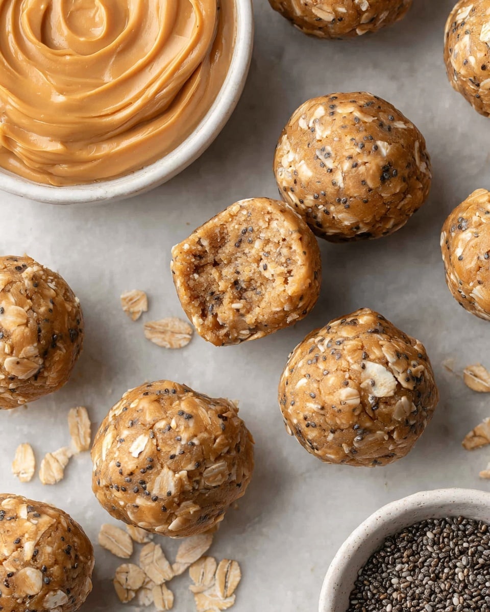 The image shows several round energy bites scattered on a white marbled surface, each ball textured with visible oat flakes and small black chia seeds mixed in a light brown base, with one ball split open to reveal a soft, dense inside filled with the same ingredients. In the top left corner, there is a white bowl filled with smooth, creamy peanut butter, its light amber color complementing the energy bites. At the bottom right corner, part of another white bowl is visible, filled with tiny, dark chia seeds, adding a contrast to the overall warm hues of the snack balls. Photo taken with an iphone --ar 4:5 --v 7