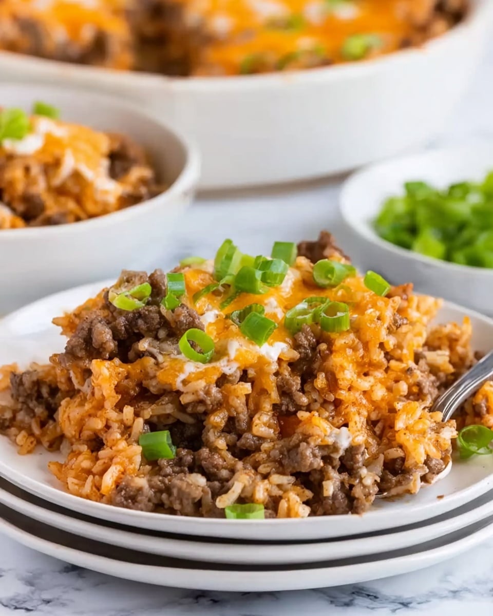 A close-up image of a white plate stacked on top of similar white plates, filled with a dish of cooked rice mixed with browned ground beef, melted cheese, and sliced green onions sprinkled on top. Behind it, there is a white bowl also filled with the same dish and a spoon inside. The dish has orange, brown, and creamy white colors from the rice, beef, and cheese, with fresh green from the onion slices. The background is a white marbled surface. Photo taken with an iphone --ar 4:5 --v 7