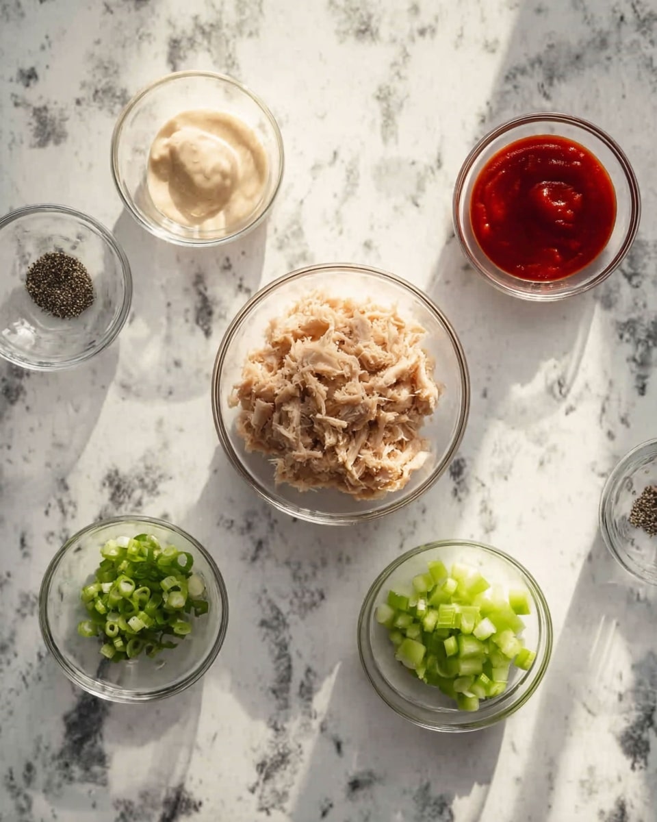 The image shows six small glass bowls arranged on a white marbled surface. The center bowl contains light brown shredded tuna. At the top left, there is a bowl with a pale cream-colored thick sauce. On the top right side, a bowl holds bright red sauce, while below it is a smaller bowl with black pepper. At the bottom left, a bowl with finely chopped green onions is visible, and beside it in the bottom middle, a bowl contains chopped light green celery. The lighting is soft and natural, and everything looks clean and organized. photo taken with an iphone --ar 4:5 --v 7