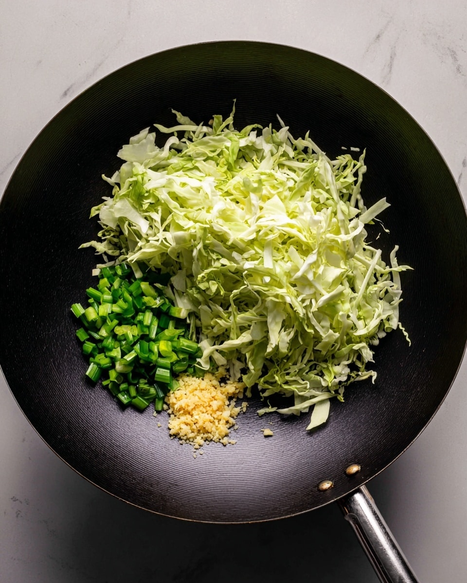A black wok sits on a white marbled surface, filled with three distinct ingredients layered to the right side. The largest layer is shredded light green cabbage, covering most of the surface with a fresh, crisp texture. Below the cabbage is a small pile of bright, chopped green onions, cut into pieces about an inch long. Next to the onions is a small amount of finely minced garlic, pale yellow in color with a slightly coarse texture. The rest of the wok is empty and clean, showing its dark, smooth interior. photo taken with an iphone --ar 4:5 --v 7