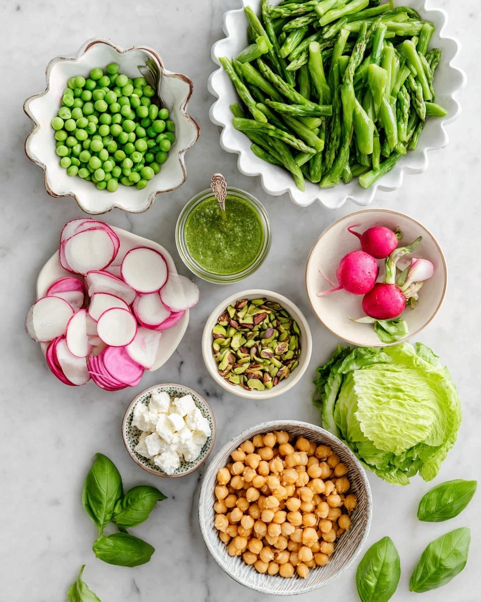 The image shows many small white bowls with fresh, colorful ingredients arranged on a white marbled surface. There is a large bowl at the top center filled with bright green chopped asparagus pieces. Below it and slightly to the left is a white scalloped bowl holding round green peas. Next to the scalloped bowl is a small round bowl with thinly sliced radishes, which are white with pink edges, and some whole radishes nearby. To the right of the asparagus is a small jar of green dressing with a spoon inside. Below the jar is a small bowl filled with chopped green pistachios. On the bottom right is a larger white bowl full of golden roasted chickpeas. To the bottom left are two small bowls, one with white crumbled cheese and another with round slices of a watermelon radish, showing a white outer edge and pink center. Bright green fresh basil leaves and smooth green butter lettuce leaves are placed near the center bottom of the frame. photo taken with an iphone --ar 4:5 --v 7