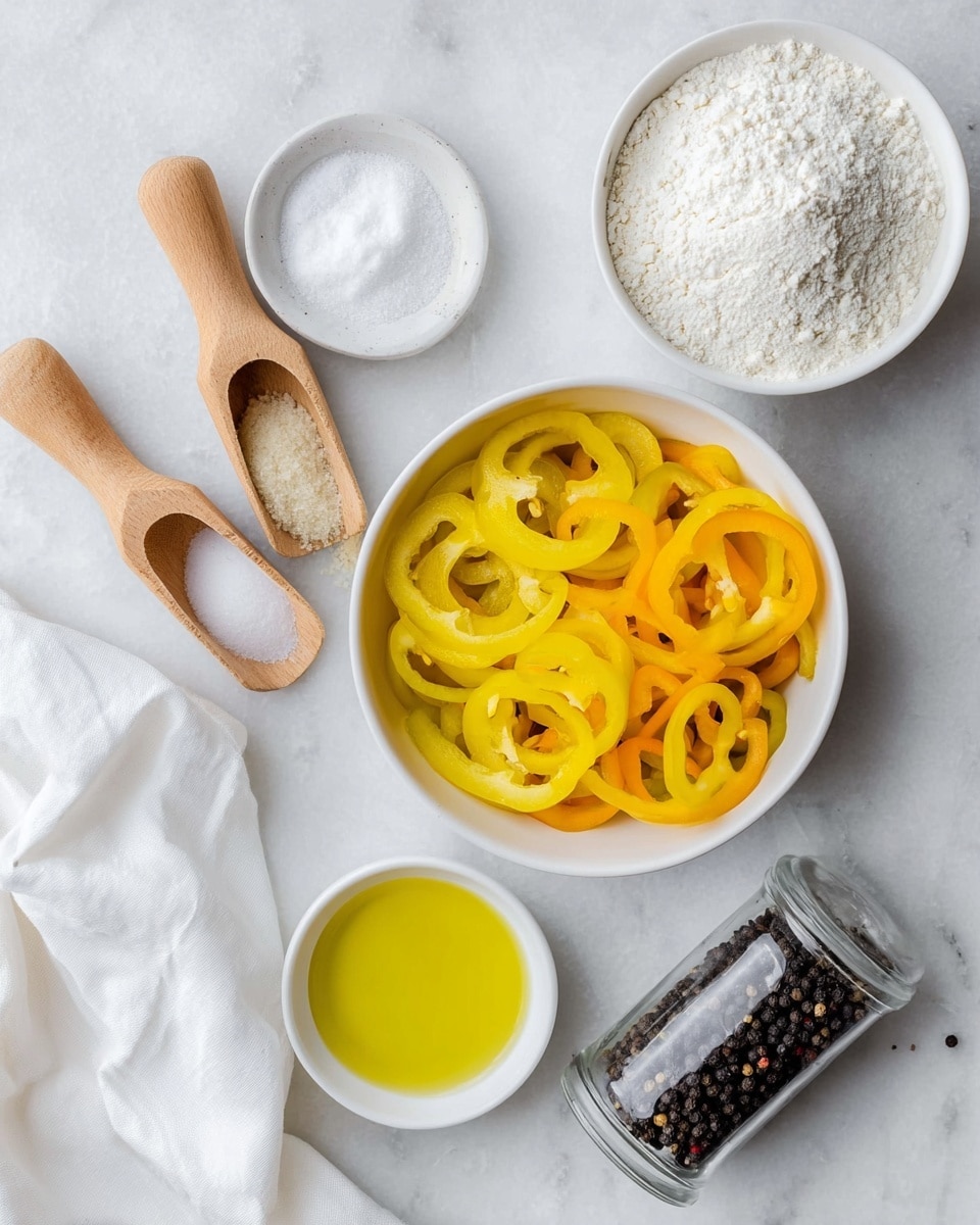 The image shows five white bowls and containers on a white marbled surface, each holding a different ingredient arranged neatly. One large round white bowl in the center contains many yellow and orange ring-shaped pepper slices stacked loosely. Above this bowl to the right is a medium-sized white bowl filled with white flour, with a powdery texture. To the left, there are two small wooden scoops, one filled with granulated garlic powder and the other with white salt. Below the large pepper bowl is a small white bowl filled with bright yellow olive oil, smooth and reflective. To the right of this is a clear pepper grinder filled with whole black peppercorns. Some white cloth is placed casually in the corners of the frame. photo taken with an iphone --ar 4:5 --v 7