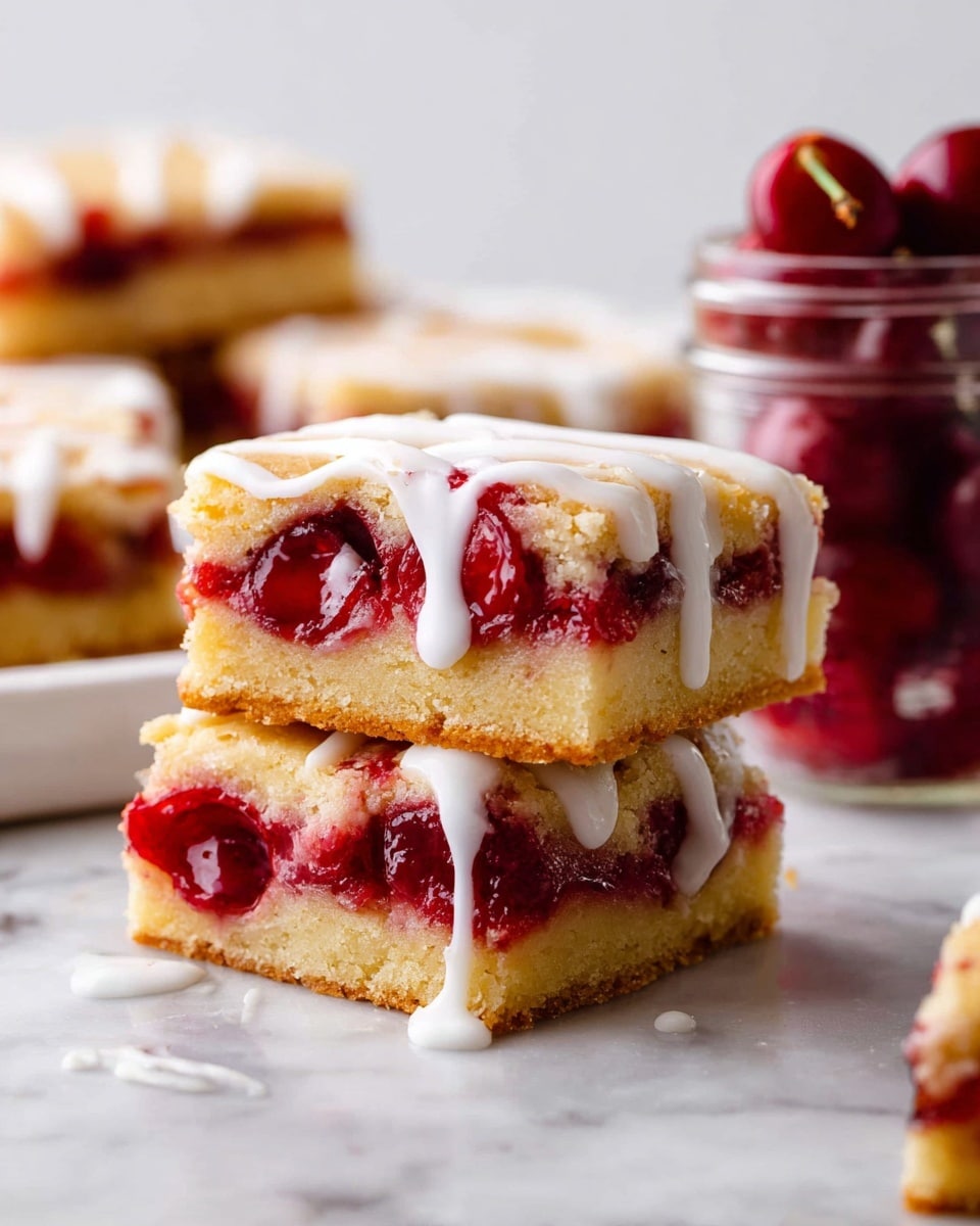 The image shows two stacked square bars with three main layers: a light golden-brown thick base with a smooth, slightly crumbly texture, a middle layer of bright red cherry filling where whole cherries and glossy juice can be seen, and a top golden layer similar to the base but thinner. White icing is drizzled over the top and sides, some of it dripping down the edges. In the background, more bars and a glass jar with cherries are visible on a white marbled surface. Photo taken with an iphone --ar 4:5 --v 7