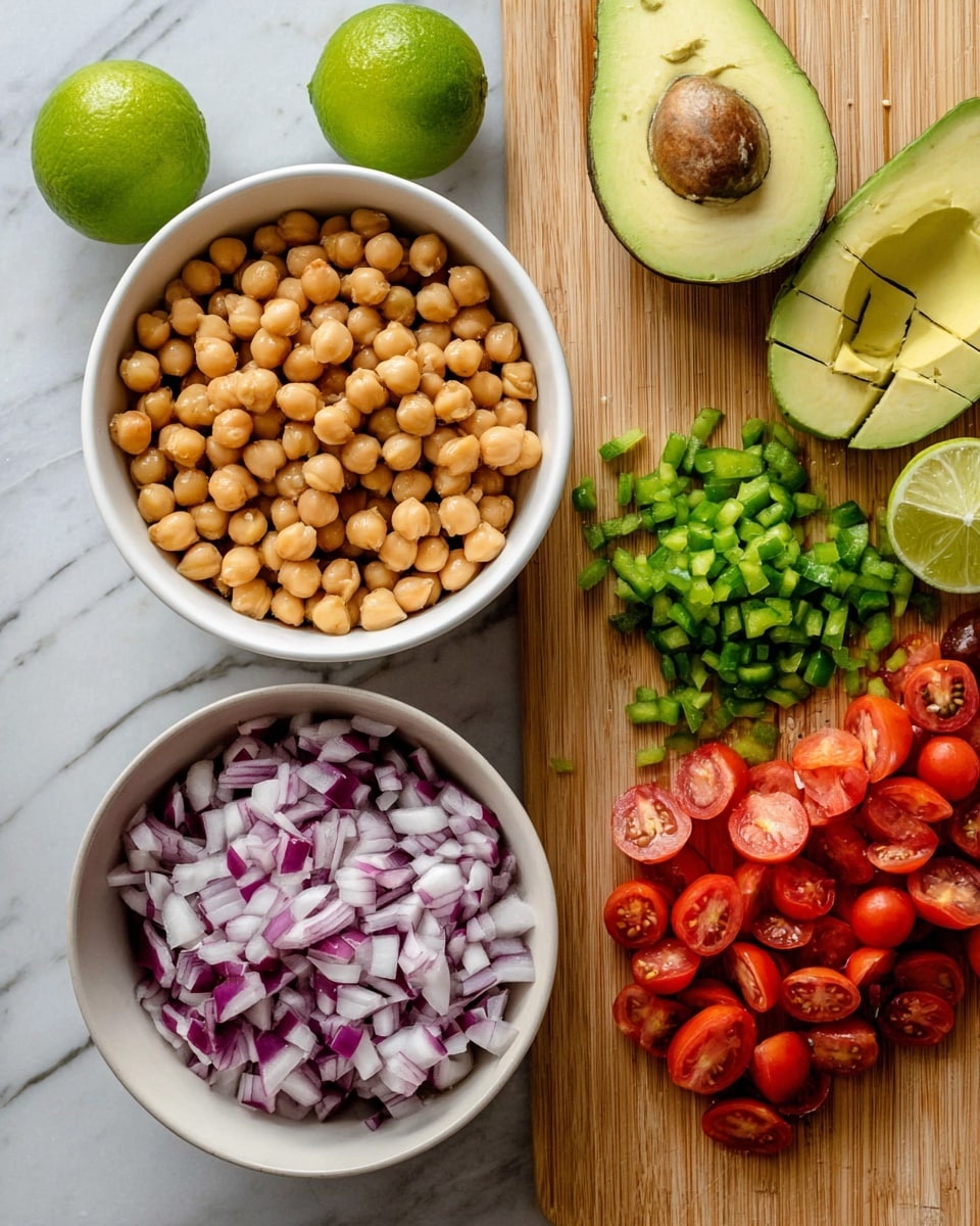The image shows two white bowls filled with cooked beans and chickpeas placed on a white marbled surface. Between the bowls, two green limes rest. A wooden cutting board on the right holds layers of fresh chopped vegetables: diced red onion with purple and white tones, finely chopped green jalapeno peppers, and halved cherry tomatoes with bright red skin and juicy interiors. At the top right corner of the board, two avocado halves are scored in a grid pattern, showing their creamy green flesh. The overall scene is bright and fresh with natural light. photo taken with an iphone --ar 4:5 --v 7