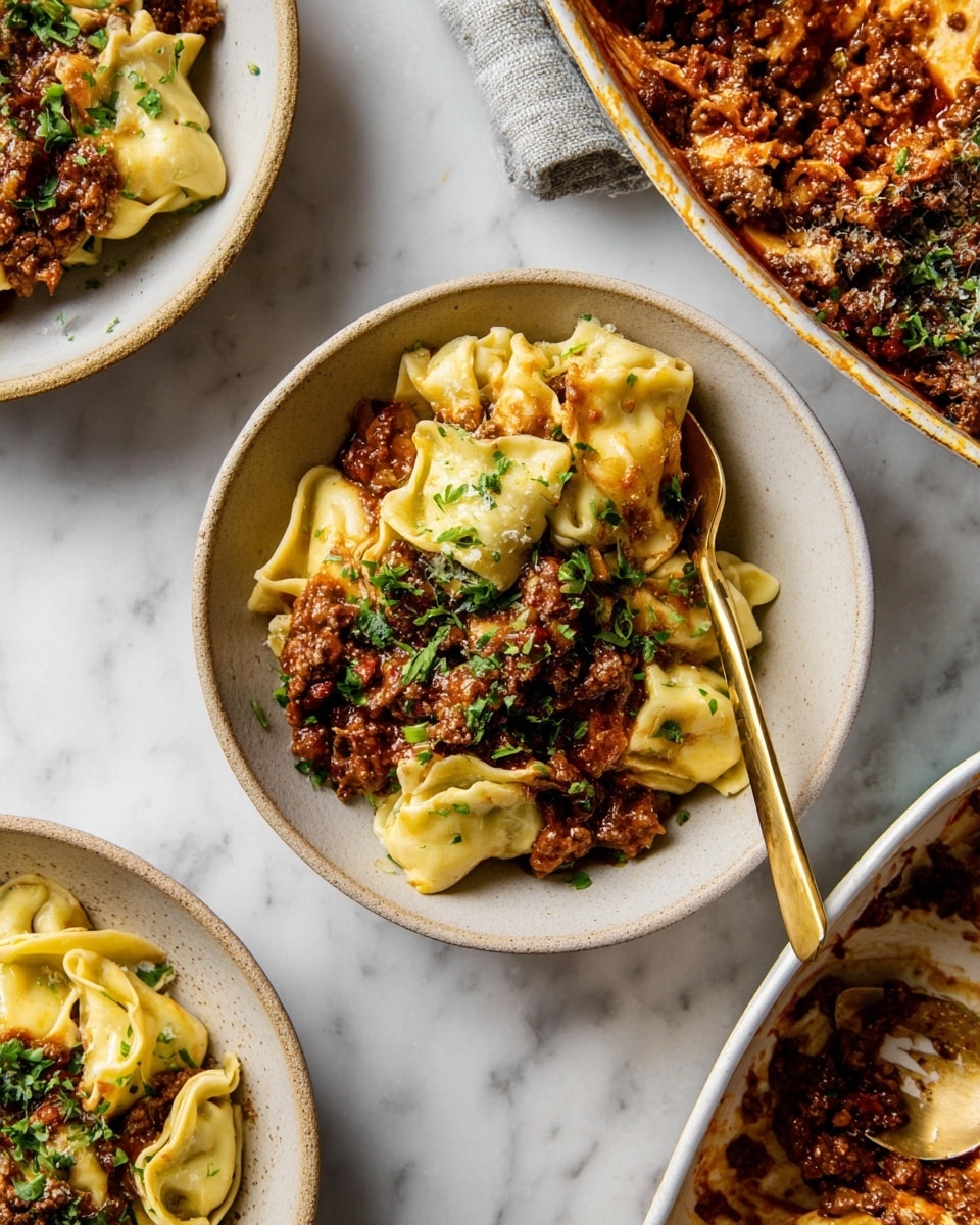 The image shows a close-up of a dish with three layers: the bottom layer is soft pasta folded into small pockets with a creamy pale yellow color, the middle layer is a rich, dark brown meat sauce with small chunks mixed evenly with onions and tomatoes, and the top layer is chopped fresh green herbs sprinkled all over, adding color contrast. The food is served in shallow white bowls placed on a white marbled surface. A golden spoon is partially inserted into the pasta in one bowl. The scene also includes a baking dish filled with the same pasta and sauce in the upper right corner. photo taken with an iphone --ar 4:5 --v 7