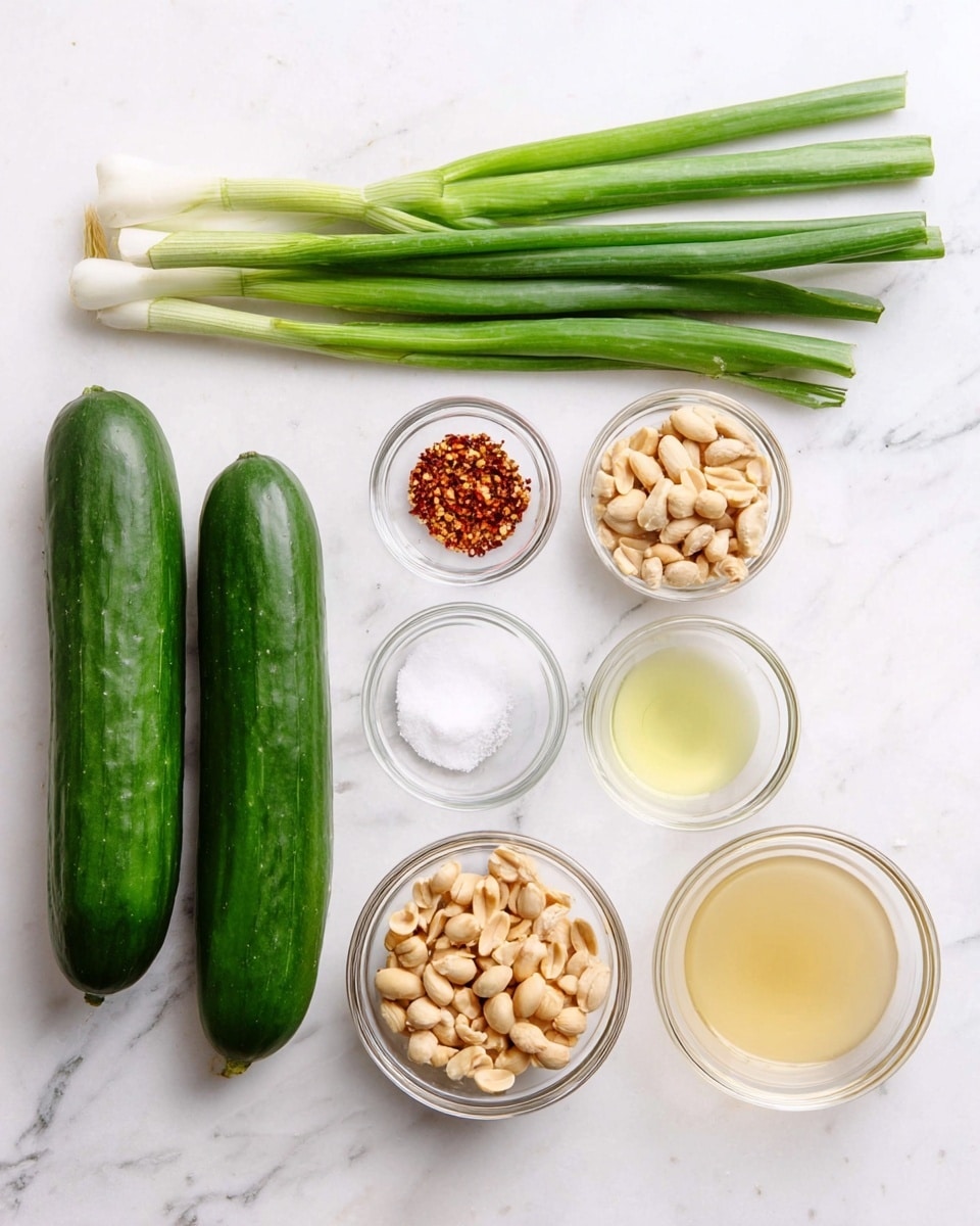 The image shows seven ingredients laid out neatly on a white marbled surface. On the left side, two long, whole cucumbers with a deep green color are placed vertically side by side. Above the cucumbers, there are three green onions with white bulbs and long green stalks laid horizontally. To the right of the cucumbers, there are five small clear glass bowls arranged in two rows: the top row has a bowl with red chili flakes, and a bowl filled with granulated white sugar; the bottom row has a bowl of roasted peanuts, a bowl with a pale yellow liquid, and a bowl with a light amber liquid. The arrangement is clean and organized, highlighting the fresh and simple ingredients. Photo taken with an iphone --ar 4:5 --v 7